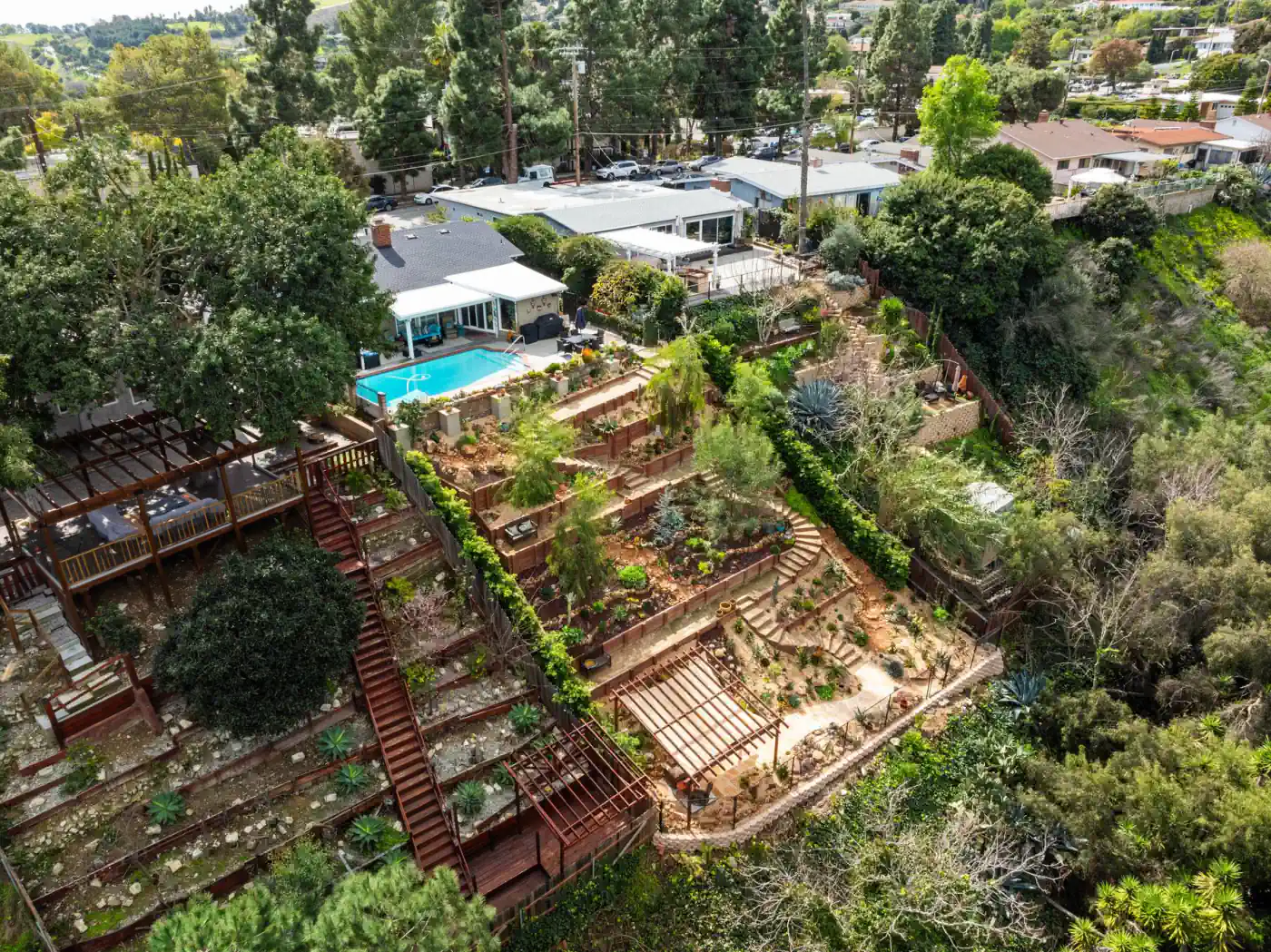 Aerial view of a Vitoli-built hillside property with tiered retaining walls and drought-tolerant planting