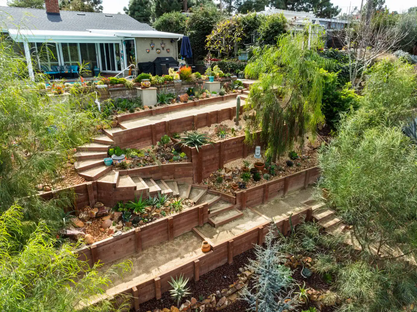 Aerial view of a hillside rear yard rebuilt with terraces, stairs, and drought-tolerant planting