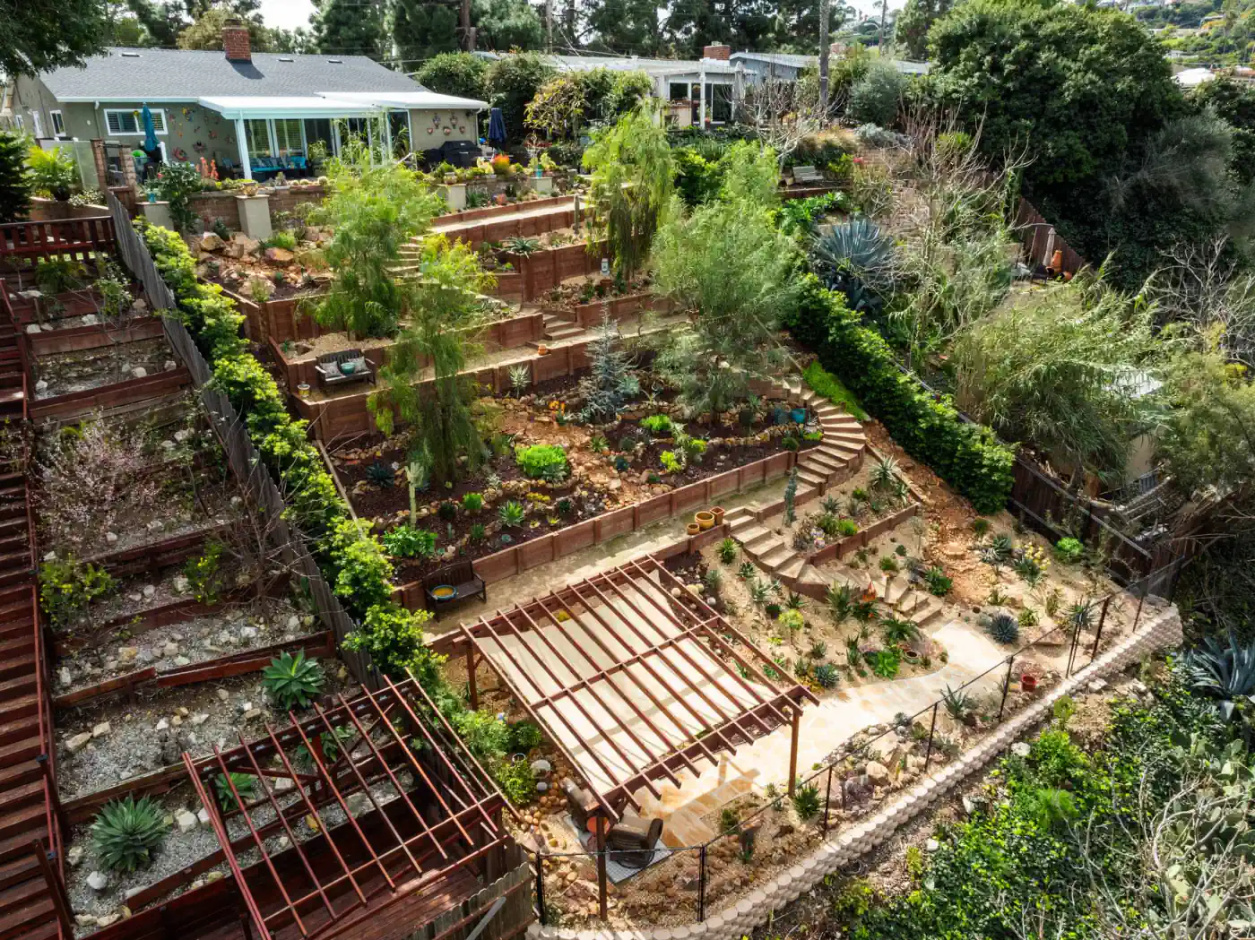 Aerial view of tiered timber retaining walls and planting beds on a hillside lot