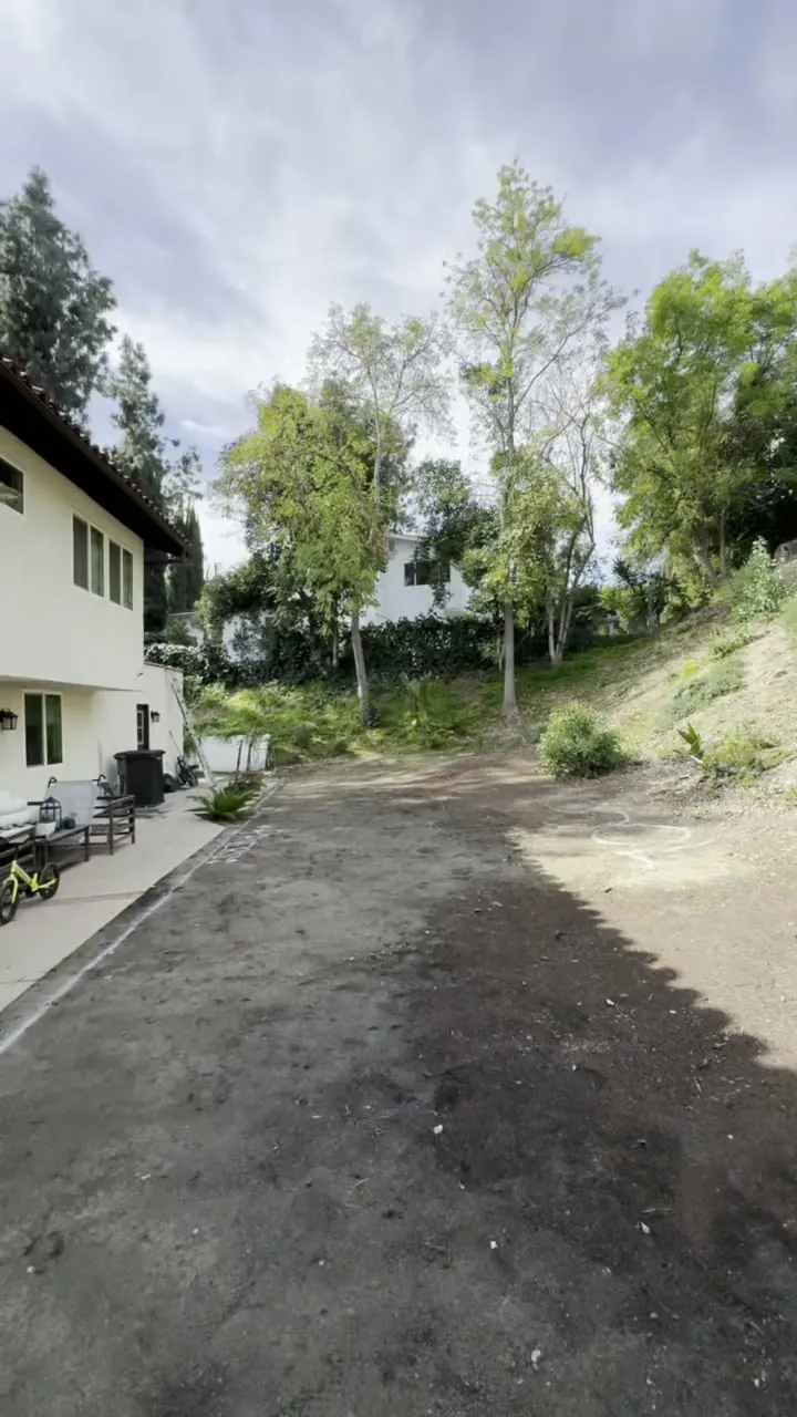 Brush-covered slope rising to the rear property line