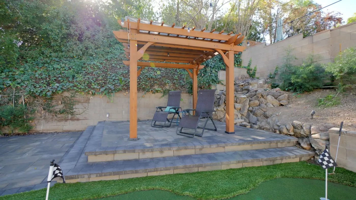 Redwood pergola on the raised paver terrace against the slope