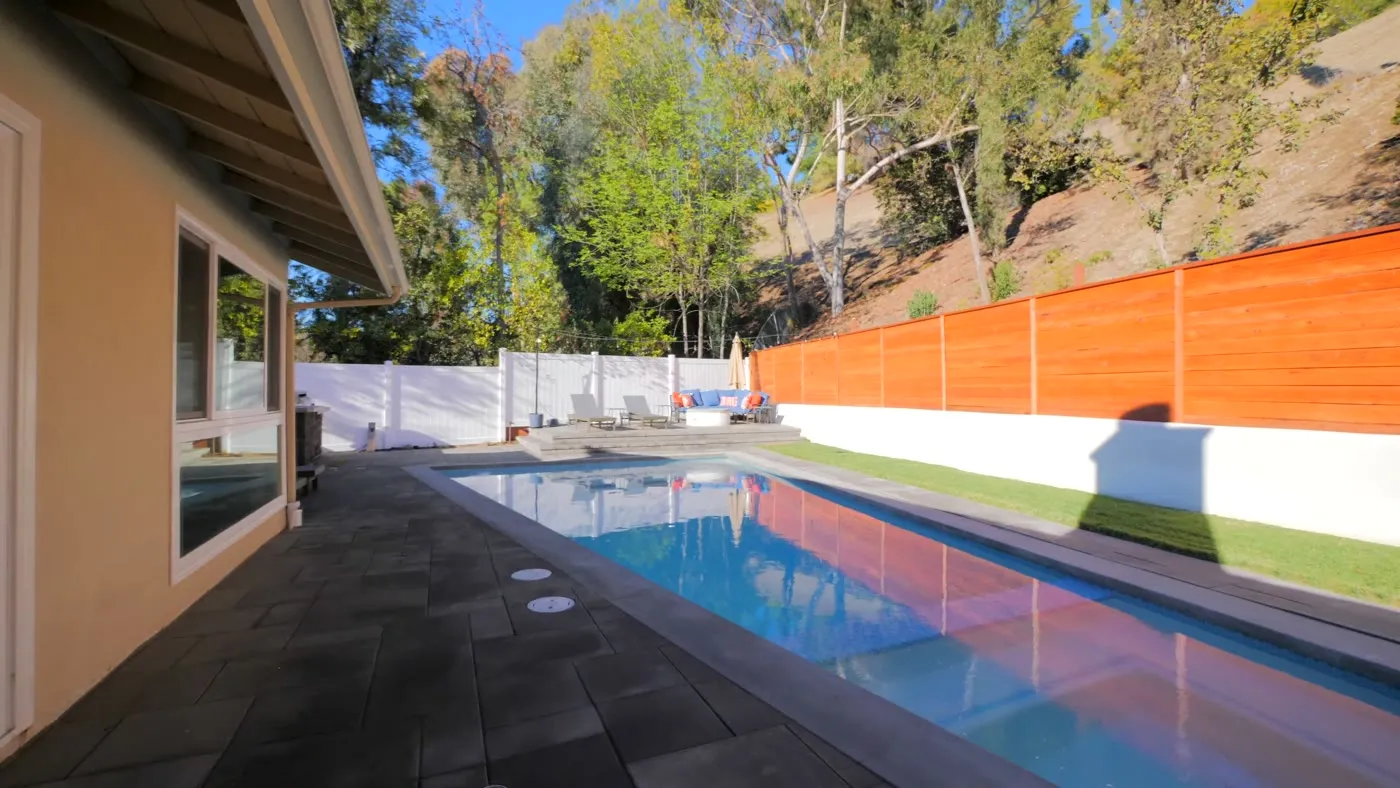Long rectangular pool and dark paver deck at the Madnick residence