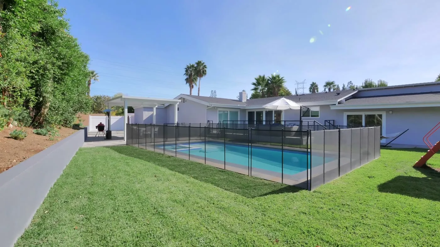 Pool deck and lawn along the rear elevation of the ranch home