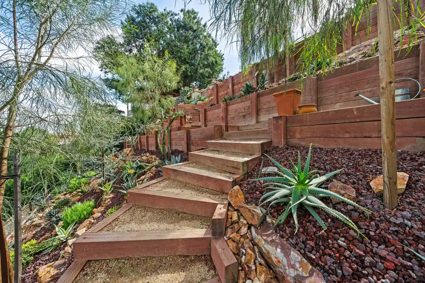 Timber stair run climbing between terraced retaining walls on a slope